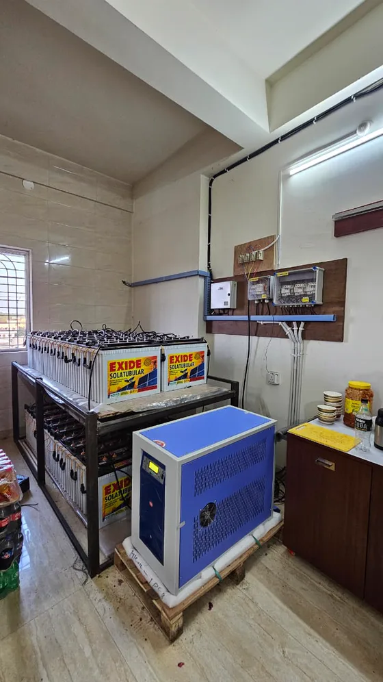 The battery rack and inverter cabinet seen from the window side, protection boxes on the wall above.