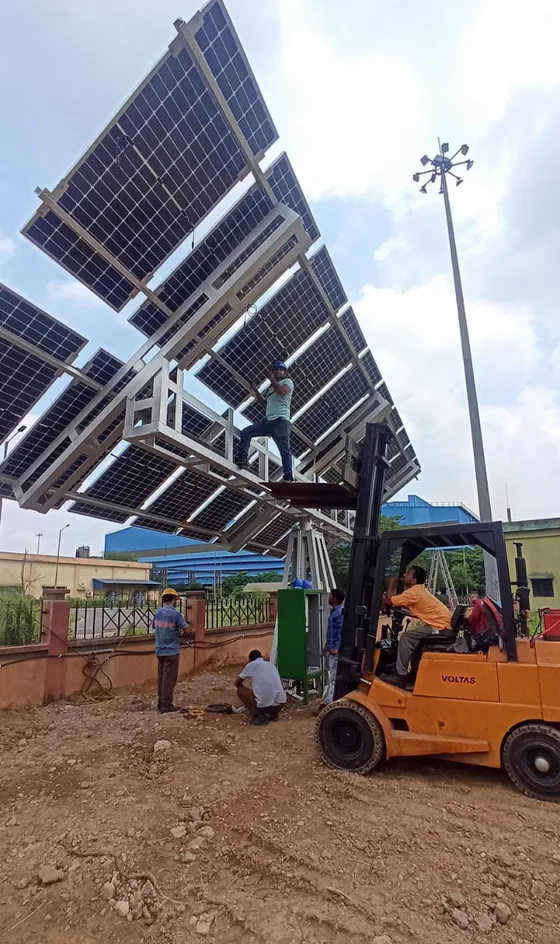Technicians fitting modules to a large elevated ground-mounted frame, one working from a forklift platform.