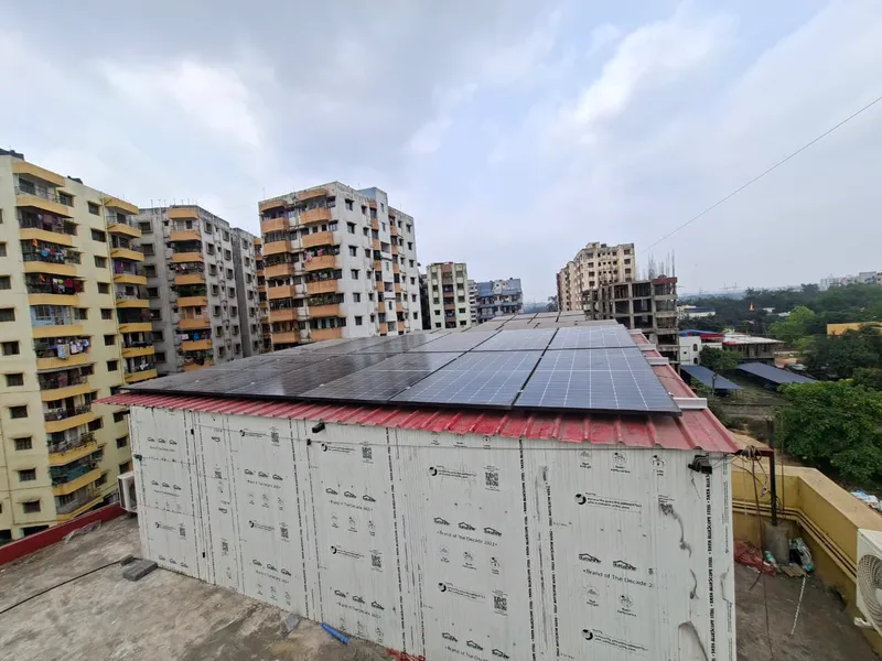 Wide view of a rooftop shed with its roof covered in solar modules, under a cloudy sky.
